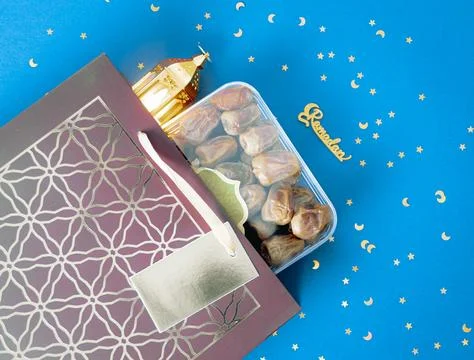 A box of dates and a lantern fall out of a shopping bag on a blue background. Foto stock