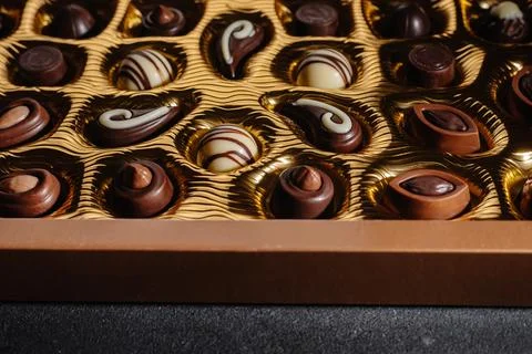 A box of different chocolates. Chocolate assortment mix on the black table, top Photos