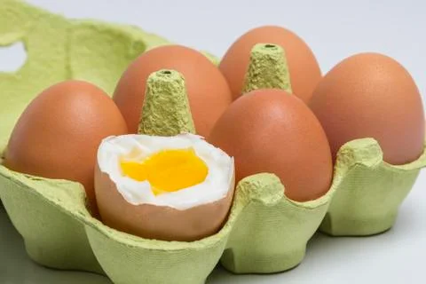Box of eggs with one broken boiled egg Stock Photos