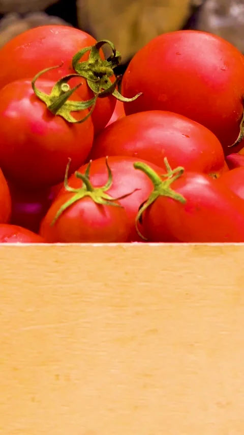 Box with fresh red tomatoes on the background of firewood. 库存影片 335145286