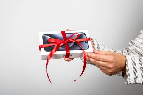 Box of the Iphone 15 Pro. Gift with a red ribbon in the hand Stock Photos