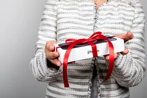 Box of the Iphone 15 Pro. Gift with a red ribbon in the hands Stock Photos
