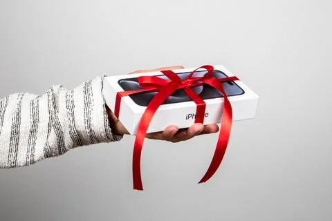 Box of the Iphone 15 Pro. Gift with a red ribbon in the hand Stock Photos