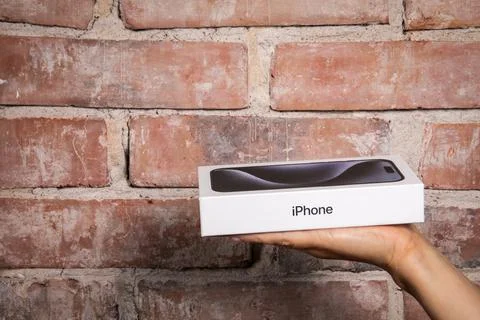 Box of the Iphone 15 Pro in the hand on a red brick background Stock Photos