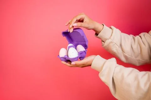 Box of light eggs in hand on pink background isolation Foto stock