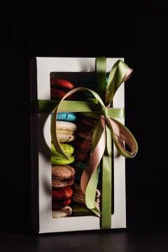 Box with macaroon cakes on a black background, tasty gift Stock Photos
