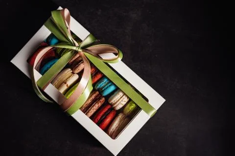 Box with macaroon cakes on a black background, tasty gift Stock Photos