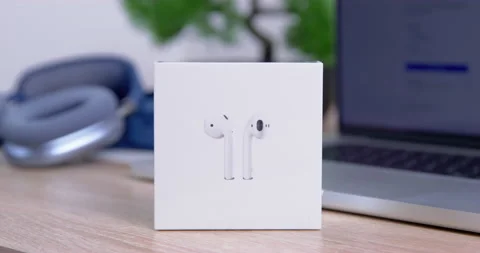 Box new Apple airpods on table against background of macbook and headphones Max Stock Footage 234471838