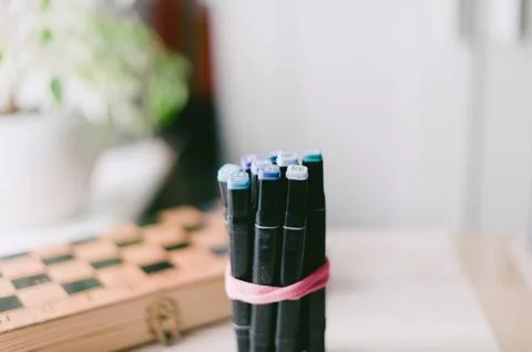 A box of pens is on a table next to a chess board Stock Photos