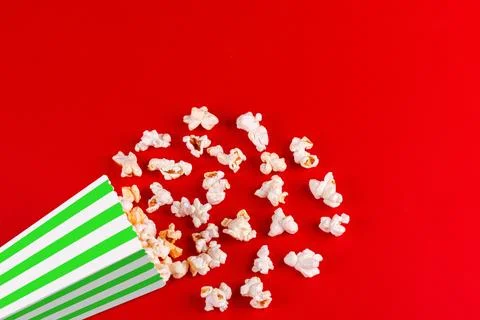 Box with popcorn striped in different colors on a red background Stock Photos