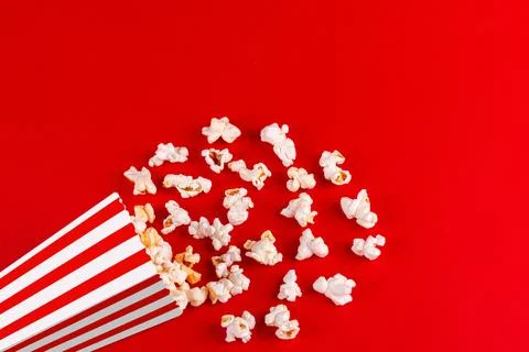 Box with popcorn striped in different colors on a red background Stock Photos