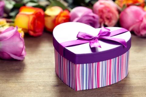 Box present on the forefront, purple and yellow roses Stock Photos