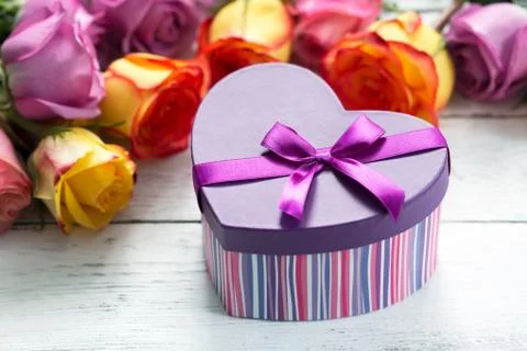 Box present on the forefront, purple and yellow roses Stock Photos