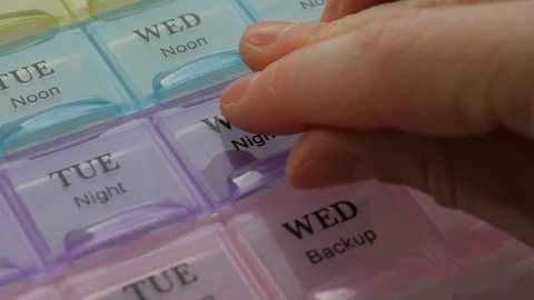 Box for the schedule of taking medications. A  hand takes a pill. Stock Footage 124632460