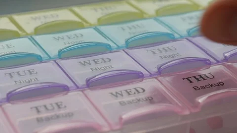 Box for the schedule of taking medications. A  hand takes a pill. Stock Footage 124770794