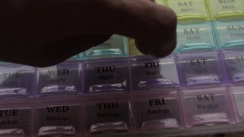 Box for the schedule of taking medications. A man's hand takes a pill. Stock Footage 84751825