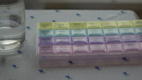 Box for the schedule of taking medications. A man's hand takes a pill. Stock Footage 84752068