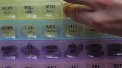 Box for the schedule of taking medications. A man's hand takes a pill. Stock Footage 84757880