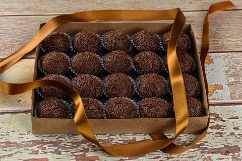 Box with several brigadeiros lined up next to a bow ribbon. Brazilian traditi Stock Photos
