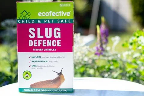 A box of Slug Defence pesticide on a white table in a garden setting Stock Photos