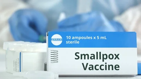 Box with smallpox vaccine on the table against blurred lab assistant. Fictional Stock Footage 126873705