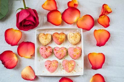 A box of sweets in the forms of hearts around the petals and rose Stock Photos