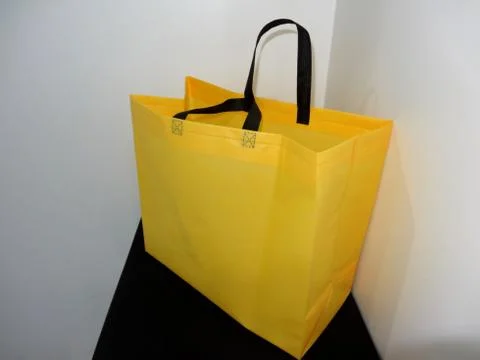 Box type polypropylene non woven eco friendly bag yellow color on black table Stock Photos