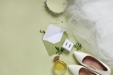 Box of wedding rings with envelope, perfume and bridal accessories on green b Stock Photos
