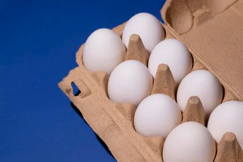 Box of white eggs on a blue background close-up Stock Photos