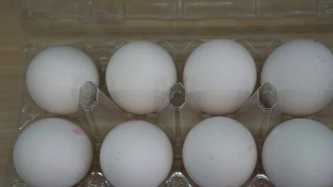 Box of white eggs in box and painted colorful Easter eggs in dish Stock Footage 113479889