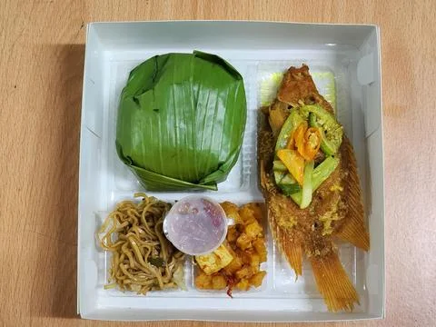 Boxed fried fish meal with side dishes and sauce top view Stock Photos