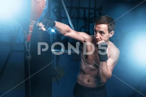 Boxer in bandages training with bag in gym Stock Photos