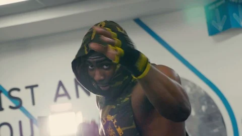 Boxer, body builder shadow boxes to camera in a sports hooded top slow mo Stock Footage 89577695