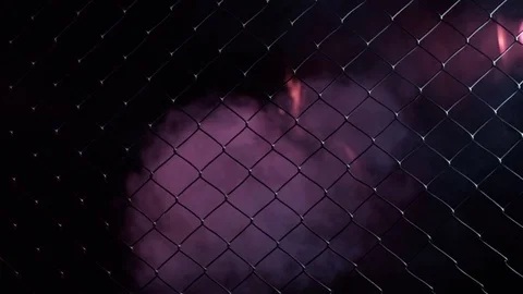 Boxer comes out of the shadows. Grabs his hands behind the net. Dark room, red Stock Footage 80862193