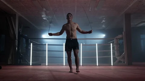 Boxer does some jump rope exercises in dark room under light. Kickboxer training Video stock 168189827
