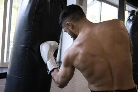 A boxer with his back turned hitting the punching bag Stock Photos
