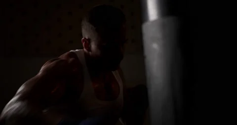 Boxer hits a punching bag in hand wraps in a dark room Stock Footage 160152452