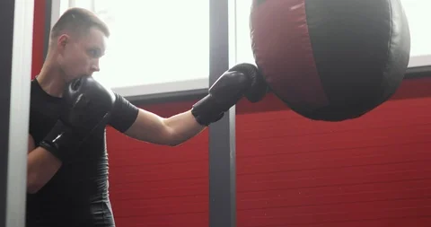 Boxer man in gloves making blows on punching bag while boxing training in gym. Stock Footage 126822128