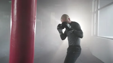 Boxer Man Hitting Heavy Red Bag during Boxing Workout in the Gym Stock Footage 174926368