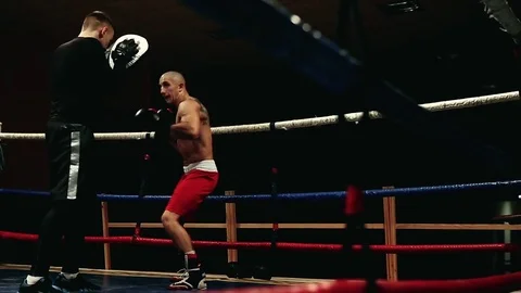 The boxer performs punches on the paws. Boxing training in the ring Stock Footage 83877265