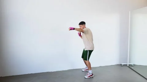 Boxer practices punches in an empty training studio during daylight hours Stock Footage 312383684