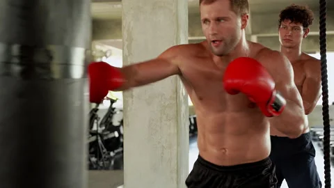 The boxer is practicing punch with sandbag and trainer teaching nearby. Stock Footage 132665225