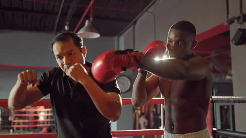 Boxer practicing punching with trainer on boxing ring Видео 254804547
