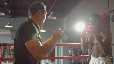 Boxer practicing punching with trainer on boxing ring Видео 254804778