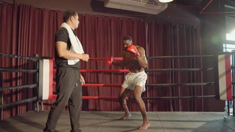 Boxer practicing punching with trainer on boxing ring Stockbeeldmateriaal 254804999