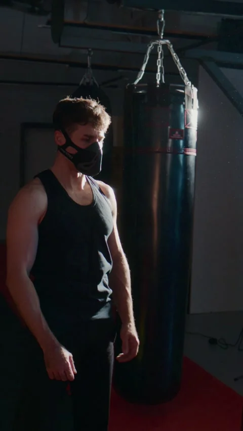 Boxer prepares for workout in dim, dramatic gym lighting Stock Footage 335506292