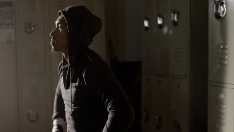 Boxer sitting on bench looking up in musty locker room 스톡 동영상 104541078