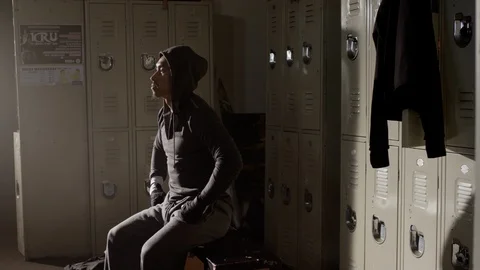 Boxer sitting on bench looking up in musty locker room 스톡 동영상 104542616