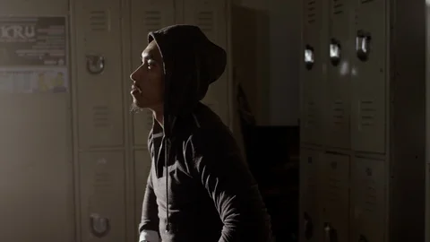 Boxer sitting on bench in musty locker room with hoodie on Stock Footage 104537550