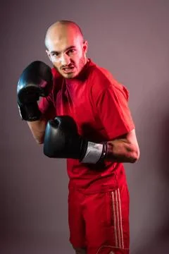A boxer stands in red clothes in the ring. blocking the blows from the coach Stock Photos